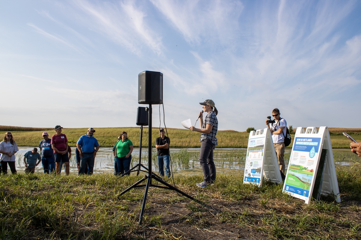 woman speaking in a crowd in front of wetland